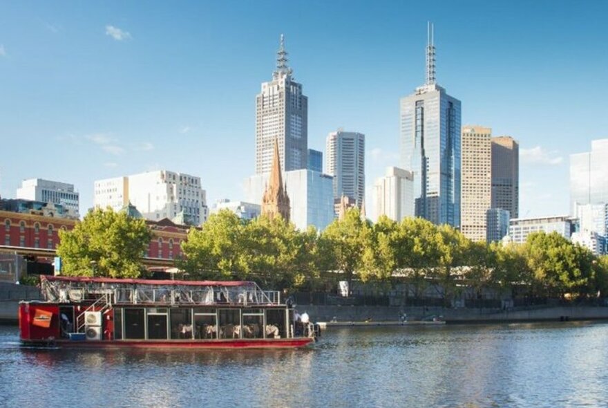 Boat on Yarra River with city scape background and blue sky.