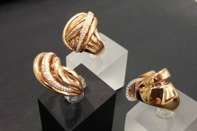 Three gold rings with small diamonds, on show stands.