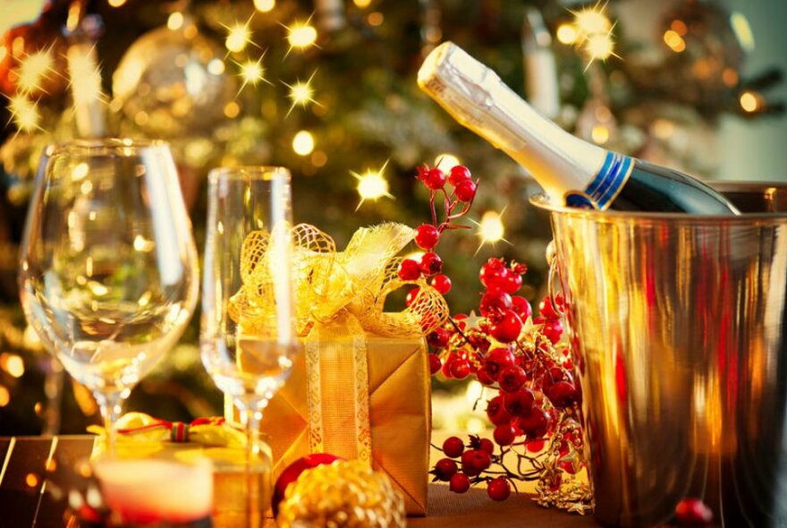 Festive table display with a bottle of champagne in an ice-bucket and wine glasses. 