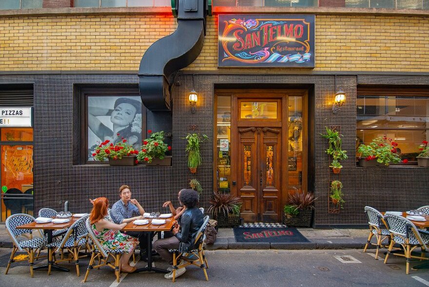 A group dining outside a restaurant in a laneway.