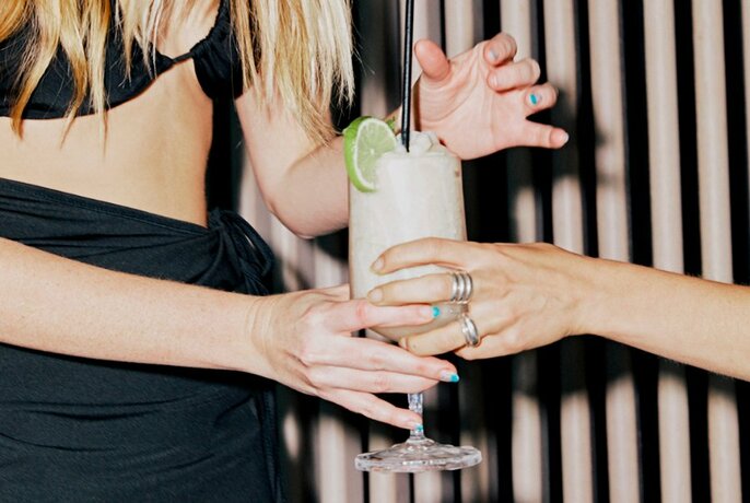 A person handing a cocktail to another set of hands. 