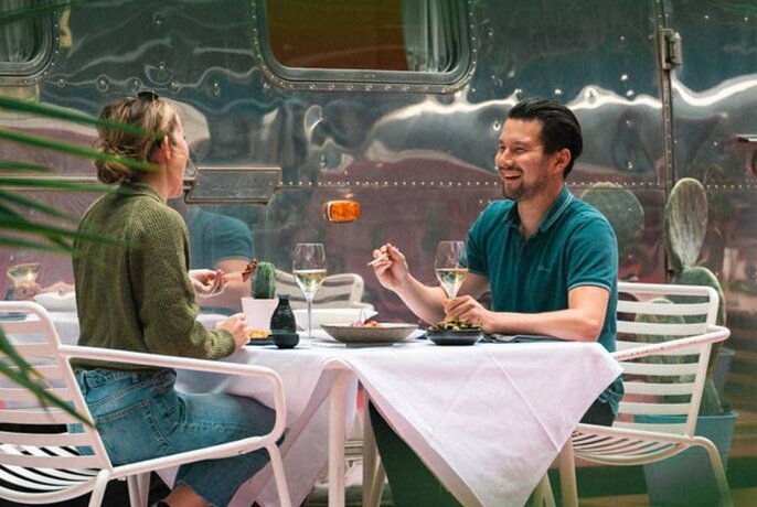 A couple enjoying a Japanese meal on a Melbourne rooftop beside vintage silver airstream trailer.