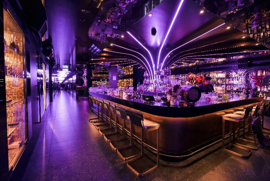 A large, central bar with purple light feature and high stools.