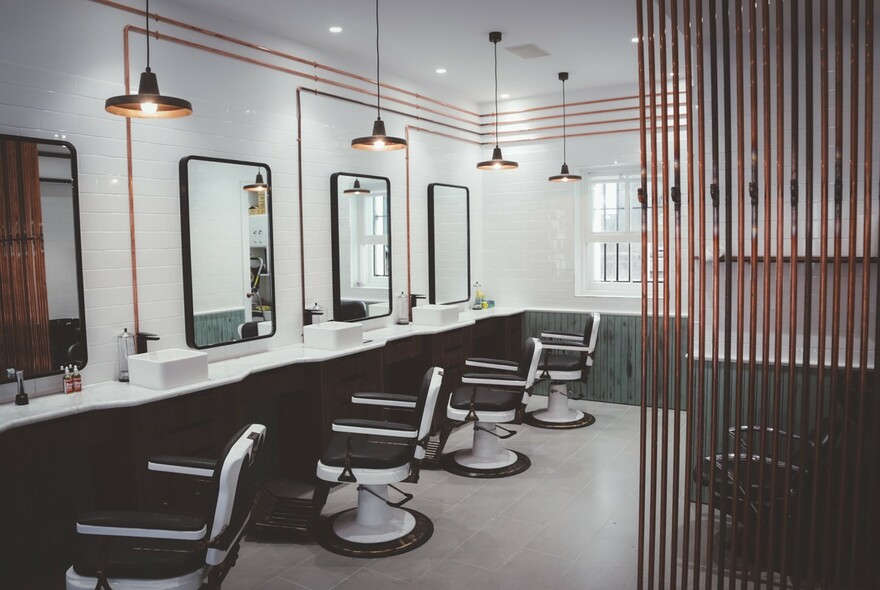 Interior of Alpha Barbers showing chairs in front of mirrors. 