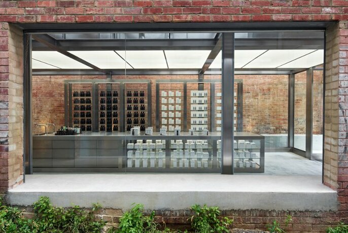 The exterior of a minimalist beauty store with bricks and metal shelving.