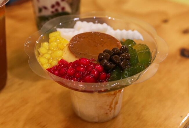 A plastic container with a flan and various jellies surrounding it