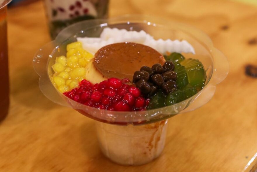 A plastic container with a flan and various jellies surrounding it