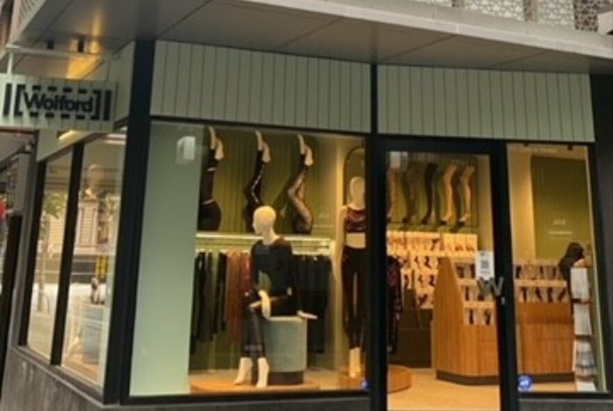 Wolford street corner view, with glimpse into store interior with mannequins and shelves.