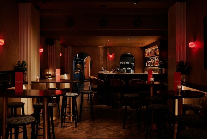 A dimly lit bar interior with wooden tables and chairs.
