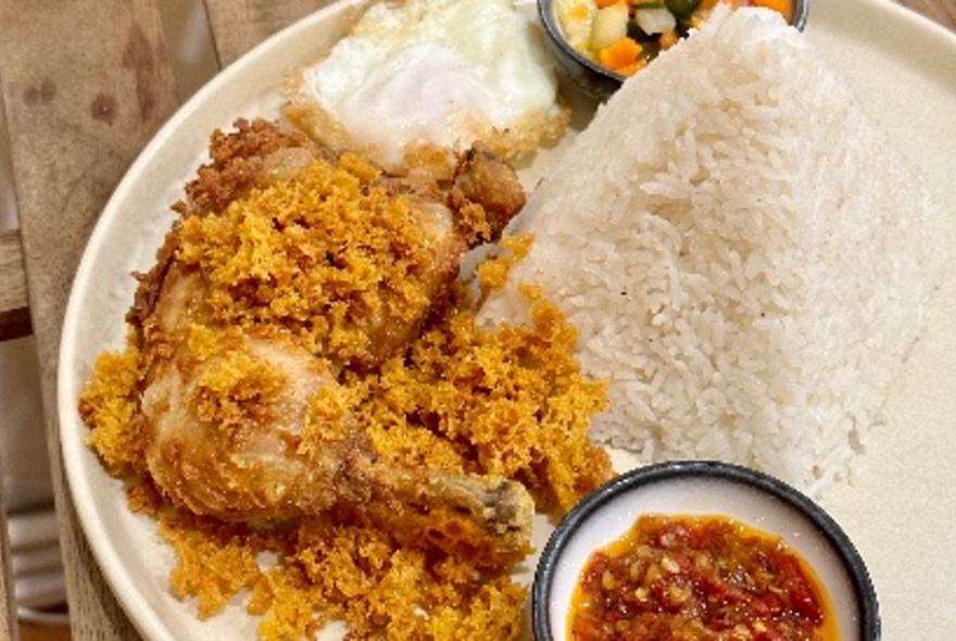 A plate of fried chicken, rice and chilli sauce.