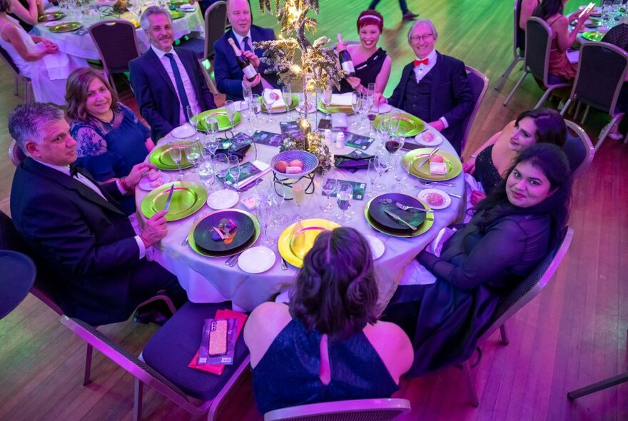 Looking down at a round table at a formal dinner with nine guests seated.