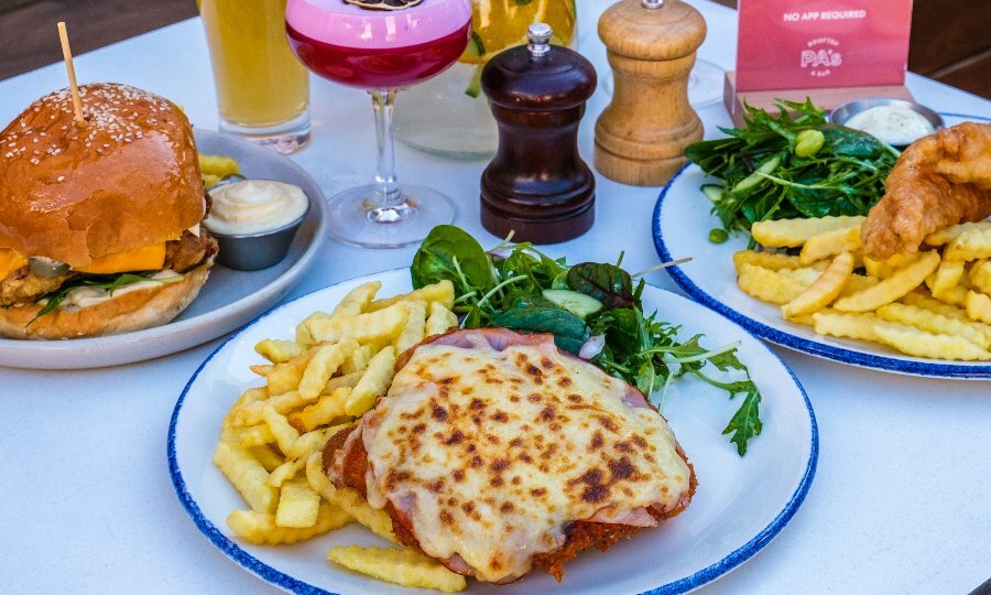 A table with burgers, a parma and a cocktail
