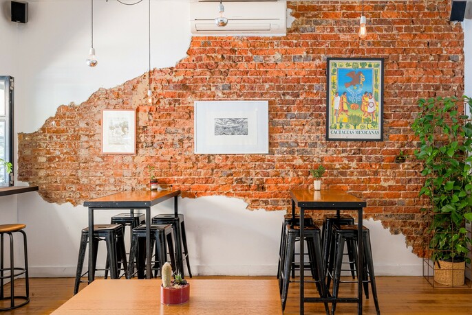Interior of Taquito with an exposed brick wall and tables with barstools. 