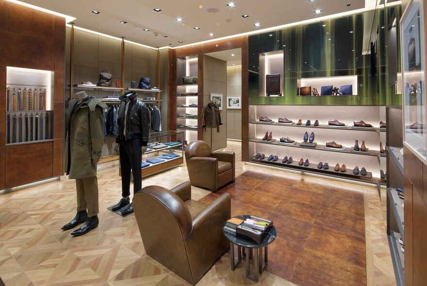 Berluti interior with mannequins, softly lit shelves with shoes and men's clothing.