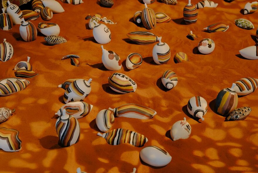 Artwork depicting many striped shells on mottled red sand.