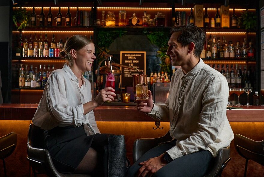 Two people enjoying a drink at a warm-coloured bar.