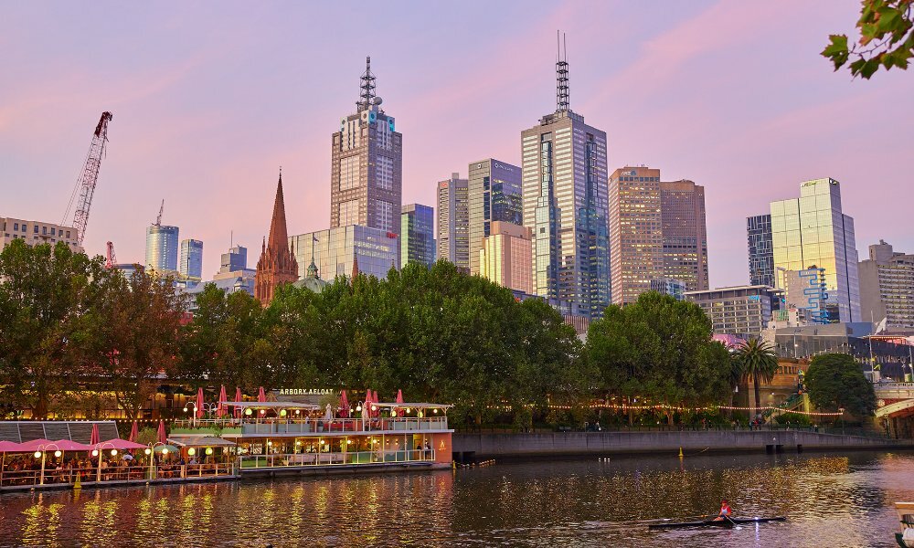 Wide shot of a floating bar on Yarra River with skyscrapers in the background.
