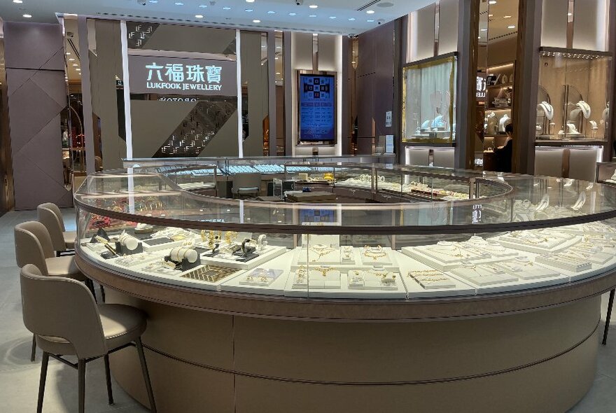 Inside a jewellery store with a circular display case and chairs. 