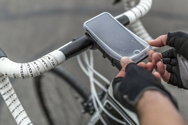Person applying protective cover to phone attached to their bicycle.
