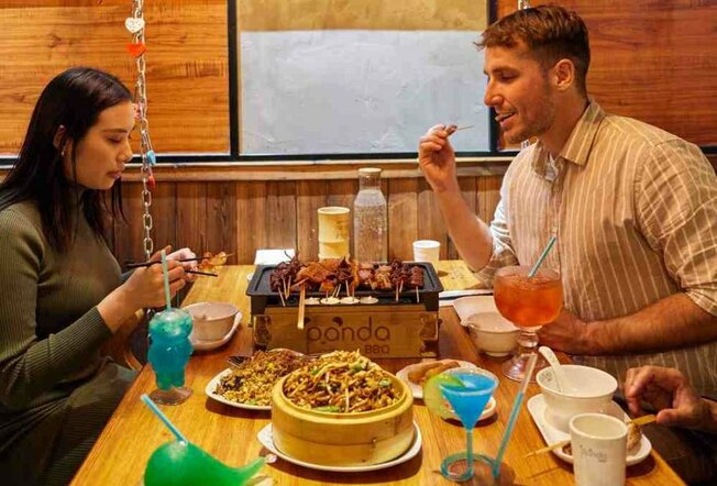 A couple sitting at a table eating asian food