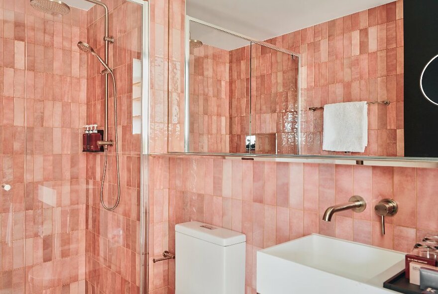 Bathroom at Quincy Hotel Melbourne with pink tiled walls and modern white amenities.