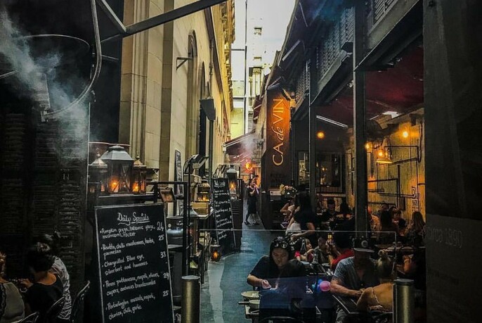 People seated in a narrow laneway cafe.