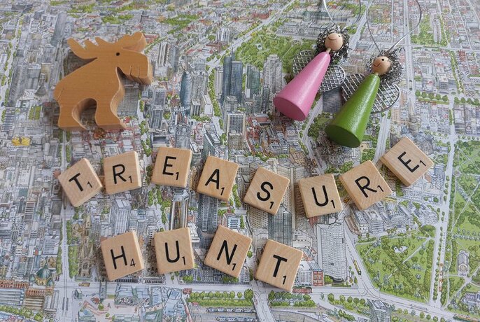 Scrabble letters spelling out 'Treasure Hunt' with wooden Christmas decorations.
