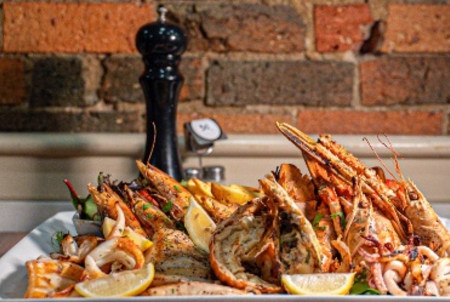 A seafood platter next to salt and pepper shakers and a brick wall.