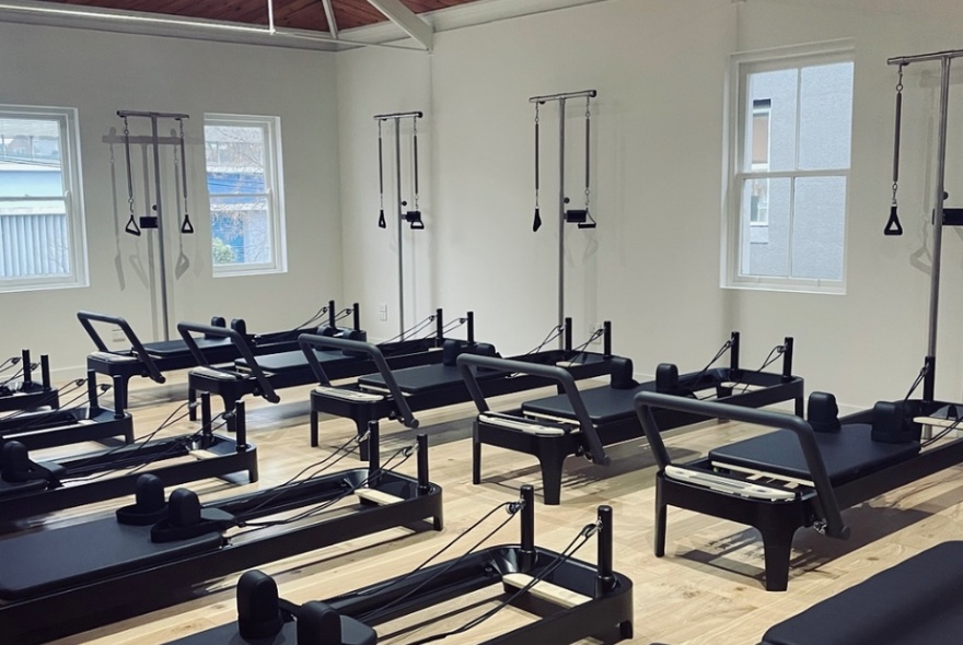 Pilates reformer machines in a white studio space.