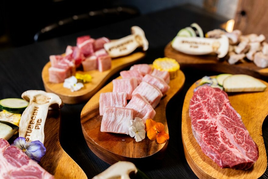 A table with small plates of various raw pork cuts.