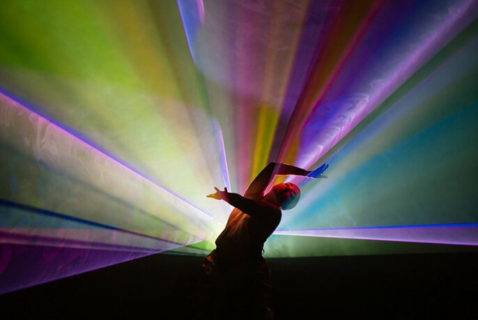 A person dancing against a backdrop of a coloured spotlight.