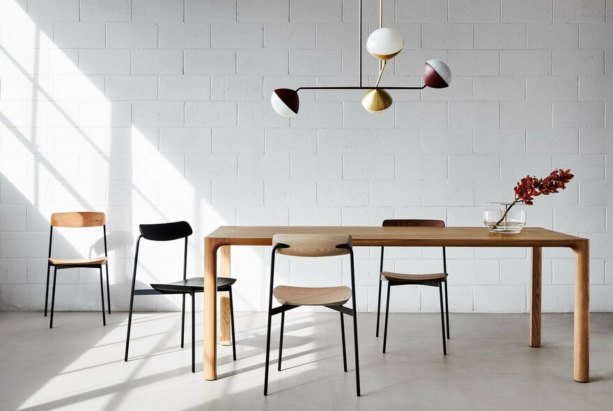 Minimalist furniture showroom with Danish wooden table, chairs and lighting.