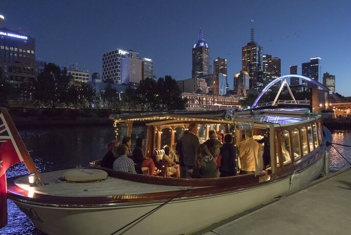 People on board a moored boat, with the Melbourne city skyline visible behind them.