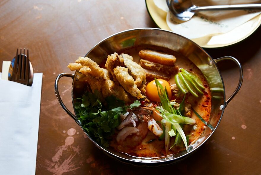 Metal, wok-like dish with curry.