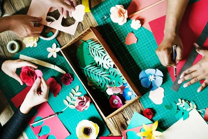 Overhead view of hands cutting and glueing paper to make decorations.