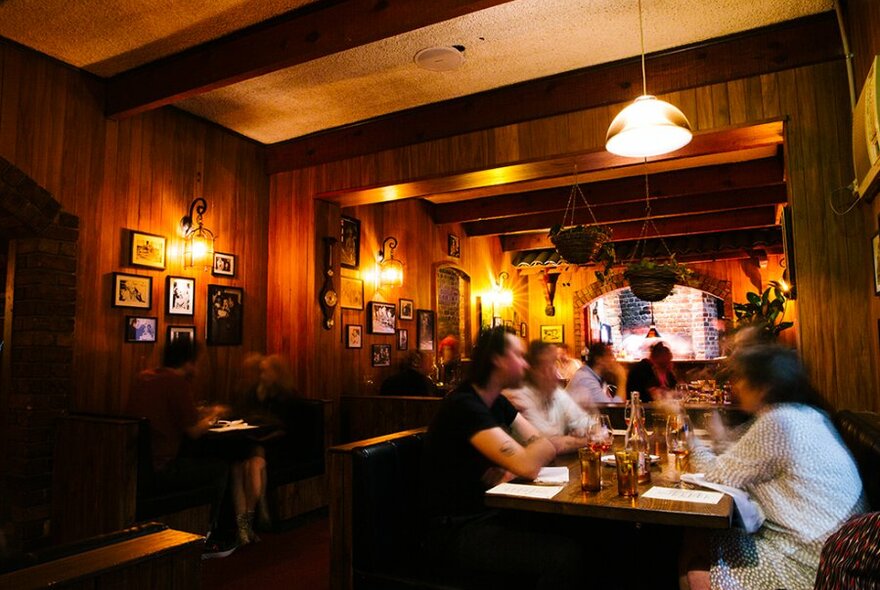 A busy and dimly lit restaurant with timber walls.