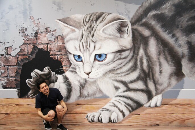Optical illusion whereby a visitor appears to be pounced on by a very large cat.