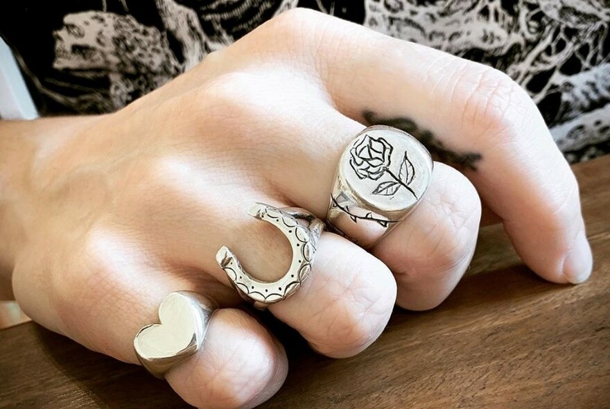 Three silver rings of varying designs being worn.