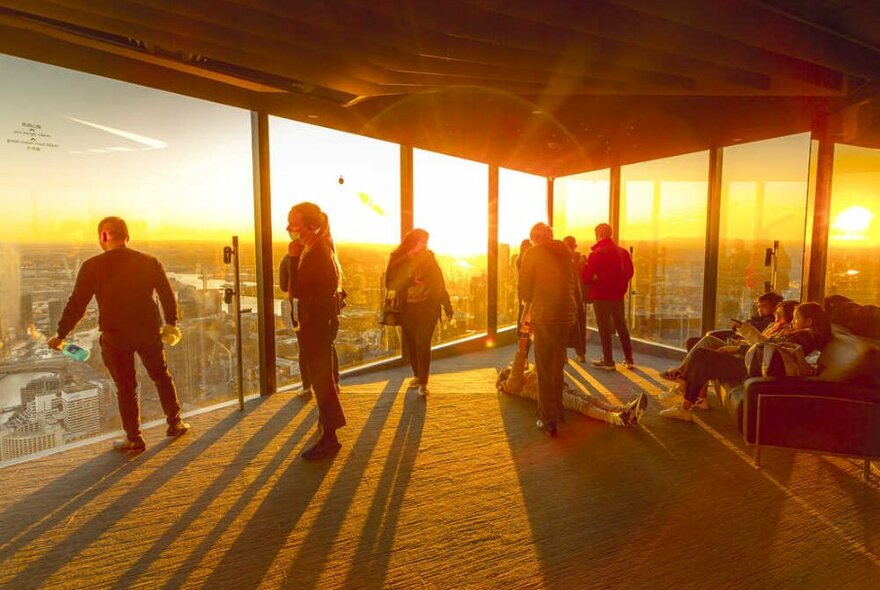 People standing on an observation deck at sunset.