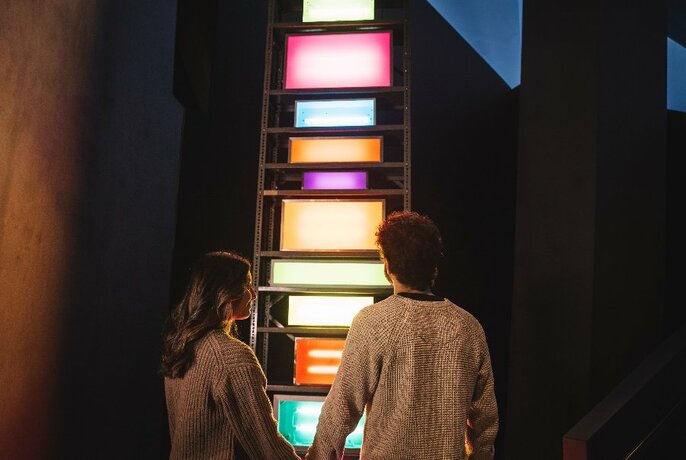 Two people looking at a colorful illuminated artwork.