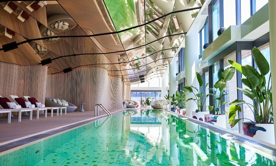 A hotel pool with a wavy silver ceiling.