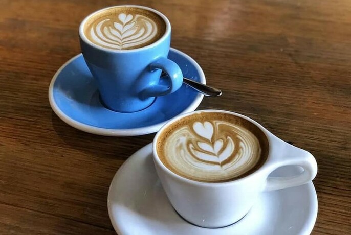 Two cups off coffee with heart-shaped coffee milk froth art.