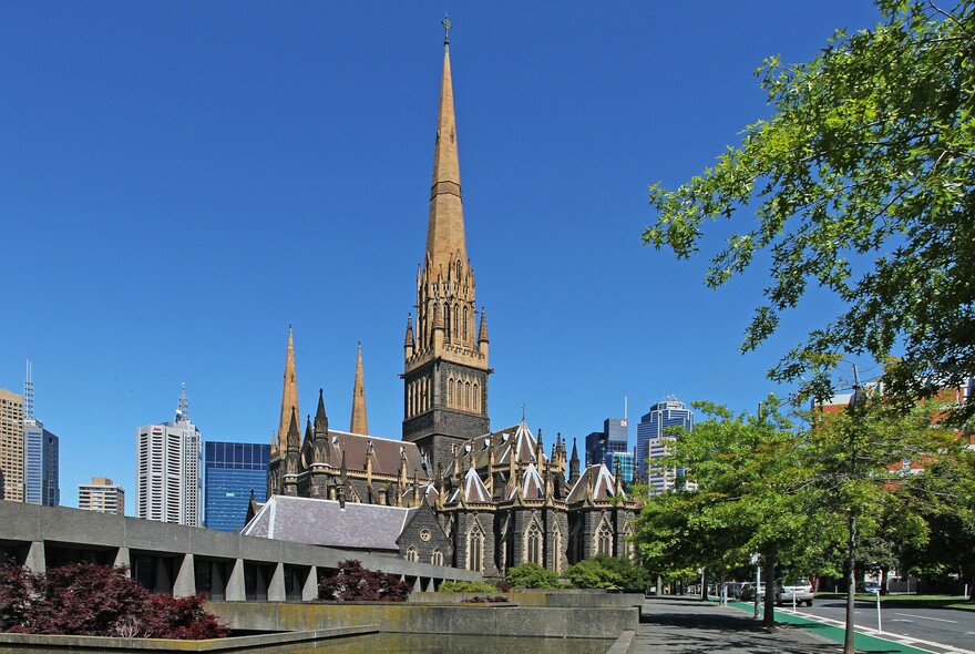 Bluestone and sandstone historic building of St Patrick's Cathedral with tall spire and Gothic revival architecture.