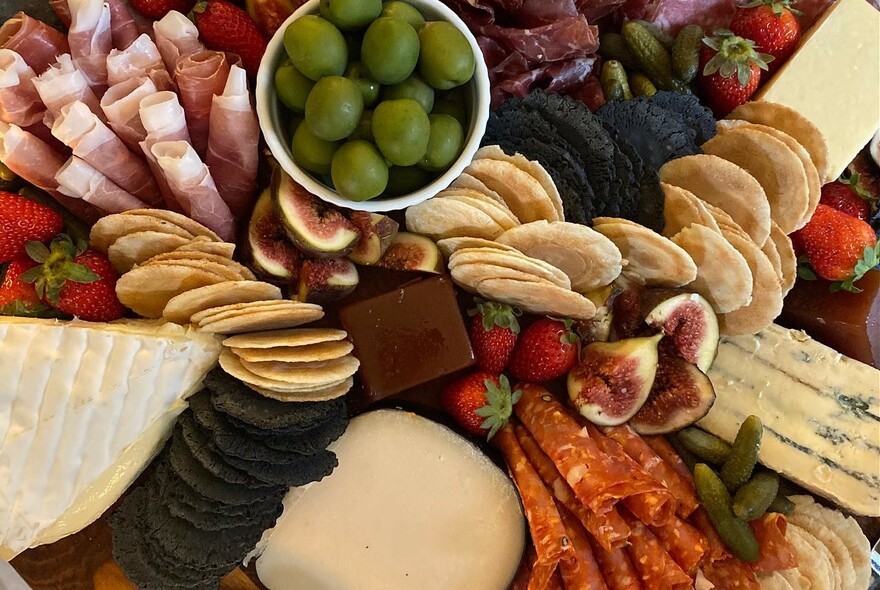 Delicatessen platter of assorted meats, olives, cheeses, fruit and crackers. 
