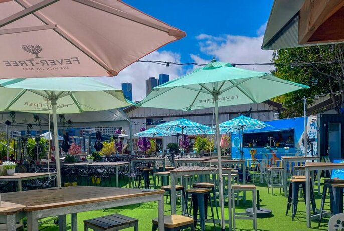 The Common Man outdoor dining and entertainment tented area with astroturf, bar tables and umbrellas.