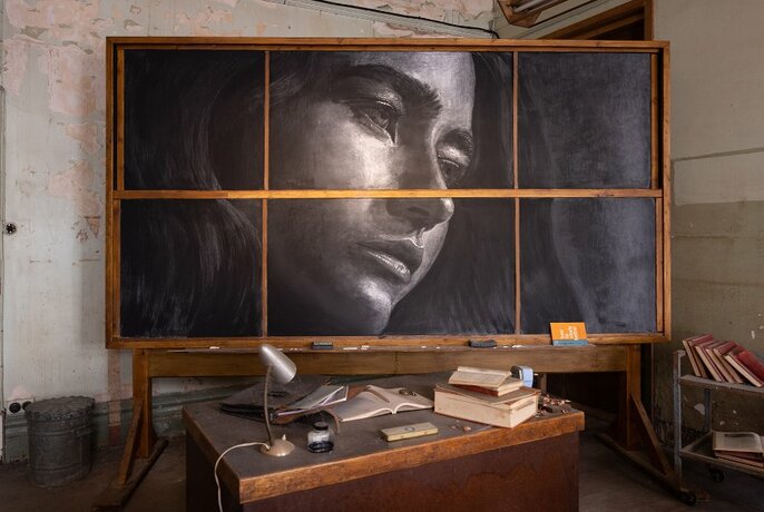A blackboard with a chalk drawing of a woman's face.