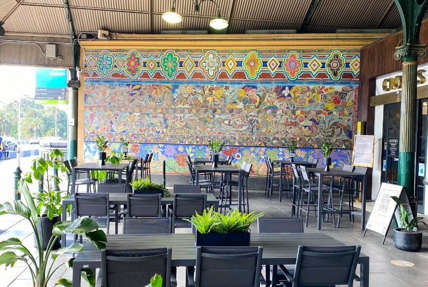 Covered outdoor cafe seating with colourful mural.