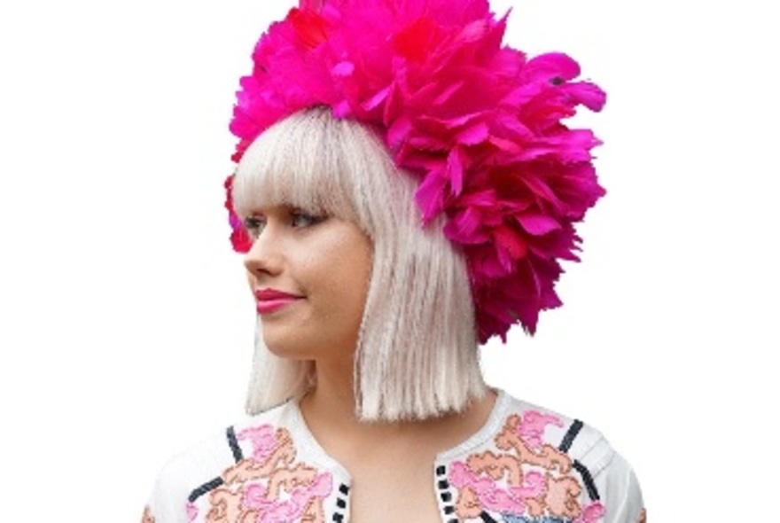 A woman wearing a bright fuschia feathered hat.
