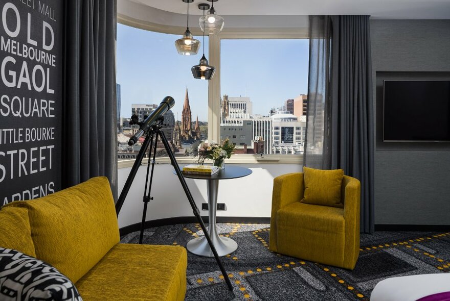 A carpeted bedroom suite in the Pullman Melbourne City Centre hotel with a curved window, a telescope on a tripod, and an armchair and couch. 