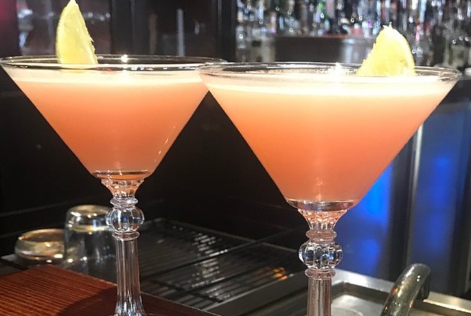 Two Cosmo cocktails on a bar.